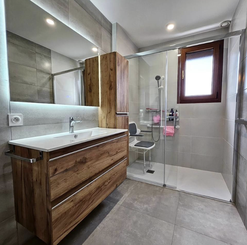 Salle de bain après rénovation : douche de plain-pied avec siège, meuble vasque bois