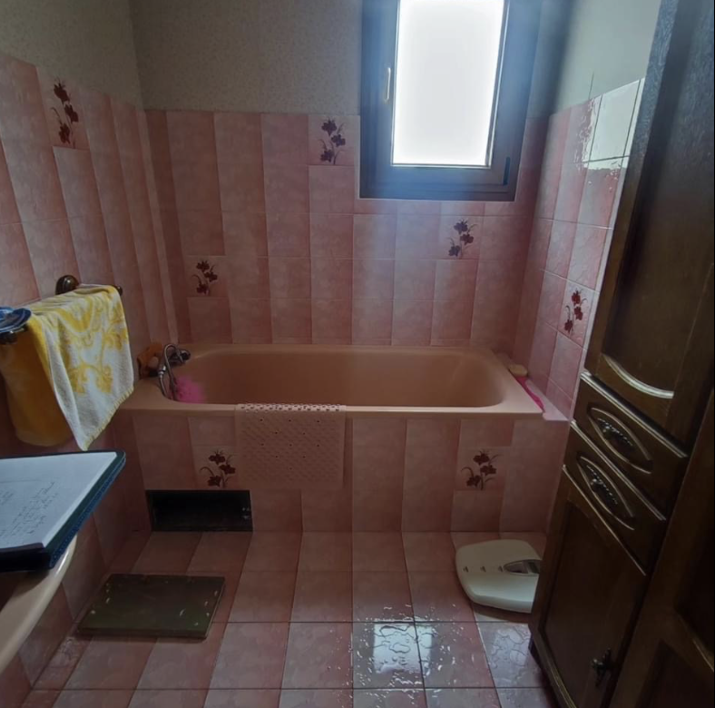 Salle de bain avant rénovation : baignoire avec carrelage rose vieillissant